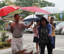 接近下午三點，下起雨來，志工連忙為家長和孩子們撐傘。【攝影者：林學群】