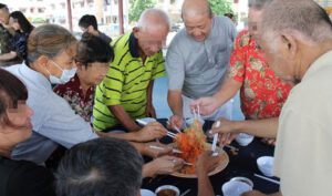 龍園組屋區場次，大家在志工們的帶領下，一起「撈生」。「撈」是粵語「拌」的意思，這是新馬一帶過農曆新年時的特色賀年食品，意喻「風生水起」及「越撈越旺」的好意頭。【攝影者：朱敏】